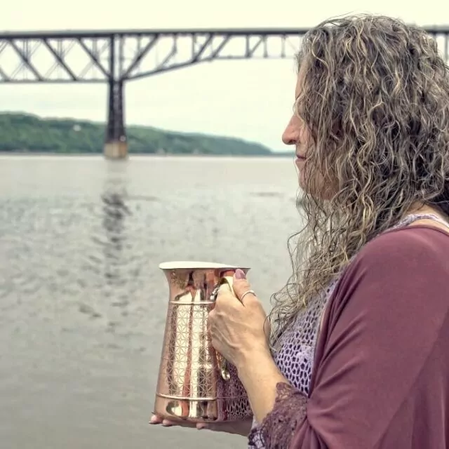 woman holding a vase near a river